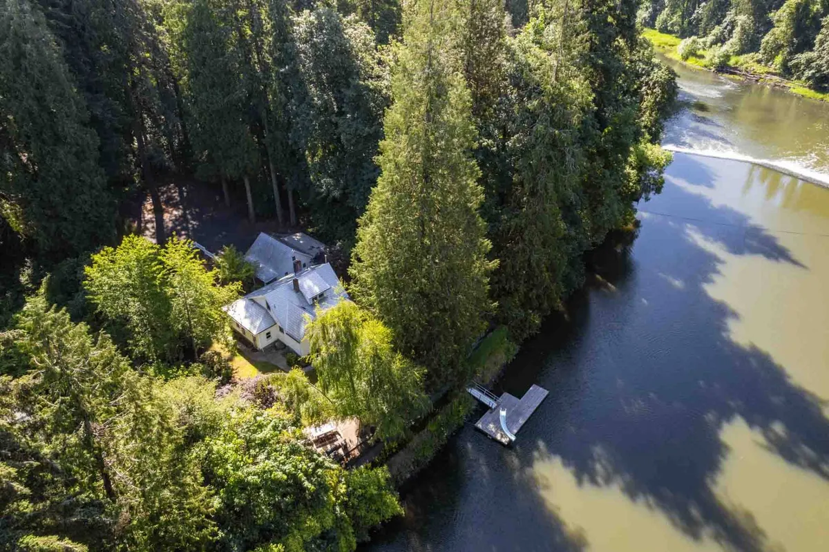 This image captures a serene stretch of the Tualatin River with a private dock extending from the house into the calm water, framed by lush trees. The tranquil setting suggests opportunities for fishing, boating, and peaceful moments by the riverbank, perfectly echoing the idea of 'river access' and immersive outdoor experiences.